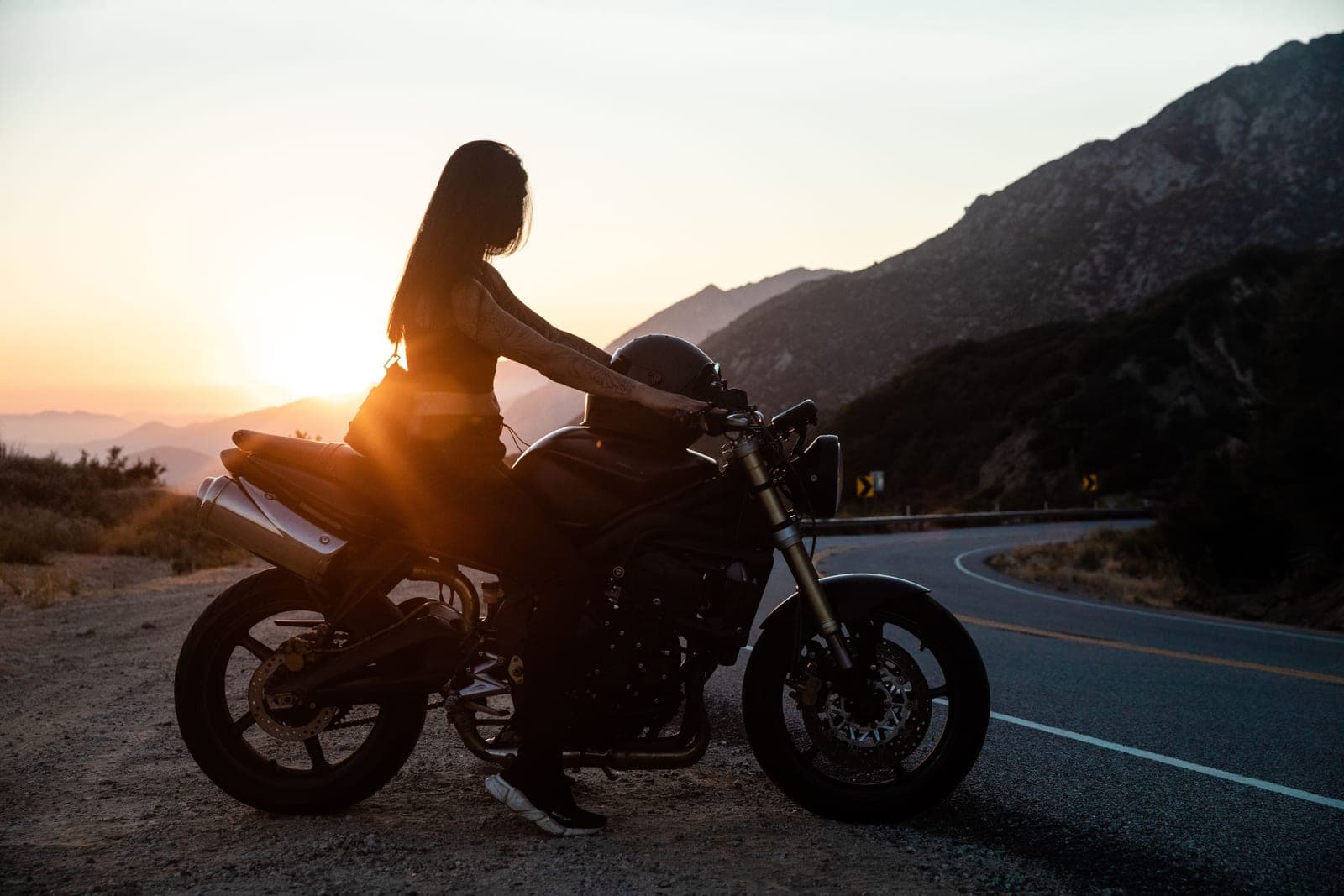Adventure motorcycle rider in a certified helmet on a mountain road at golden hour