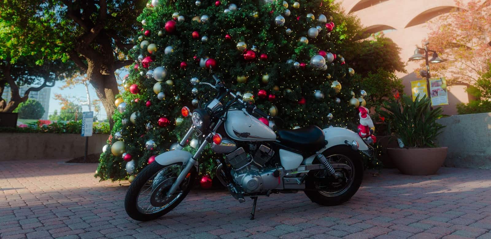 A motorcycle parked in front of a decorated Christmas tree